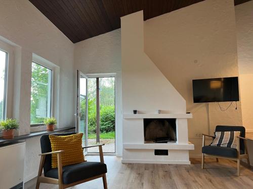 Una sala de estar con dos sillas y una chimenea. en Landhaus 918, en Koosbüsch