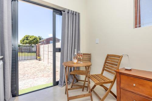 a room with a table and a chair and a window at Blouberg Studio Apartments in Bloubergstrand