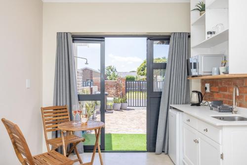 a kitchen with a table and chairs and a window at Blouberg Studio Apartments in Bloubergstrand