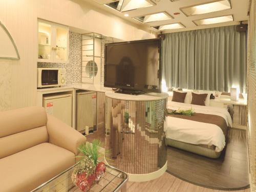 a living room with a large television and a bedroom at HOTEL CHANT - Adult Only 大人専用 in Sakai