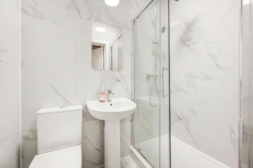 y baño blanco con lavabo y ducha. en 2 bedroom apartment with large rooms and Wi-Fi, en Londres