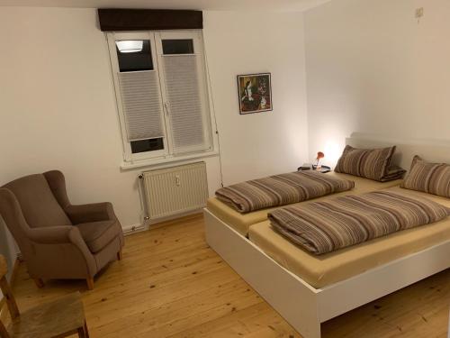 a bedroom with a bed and a chair at Daheim am Rhein - Schöne 2 ½ Zimmer mit Balkon in Küssaberg