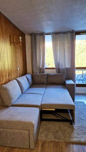 - un salon avec un grand canapé et des fenêtres dans l'établissement Studio avec vue imprenable sur la montagne à Isola, 25 m²., à Isola