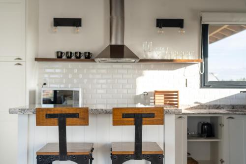 a kitchen with a counter with two wooden stools at Los Alerces Resort, Hotel & Spa in San Andres de las Sierras