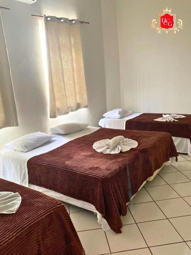 a hotel room with two beds with brown blankets at Hotel Central Campo Grande in Campo Grande