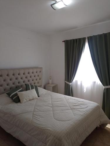 Schlafzimmer mit einem großen weißen Bett und einem Fenster in der Unterkunft Depto Cuca y Andrés in Cerro de Oro
