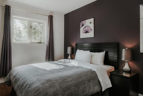 a bedroom with a large bed and two windows at Royal Laurentien in Mont-Blanc