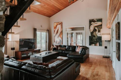 a living room with black leather furniture and paintings at Royal Laurentien in Mont-Blanc