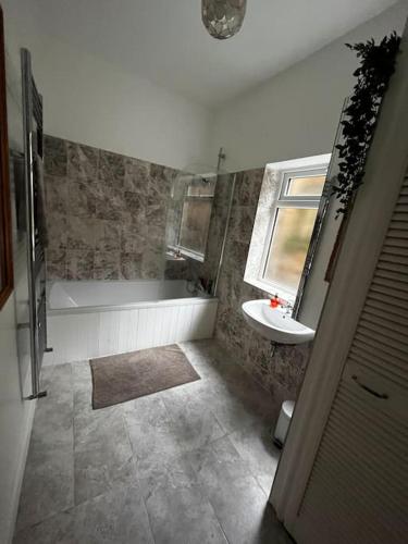 a bathroom with a tub and a sink at 3 Bed Ground Floor Flat in London