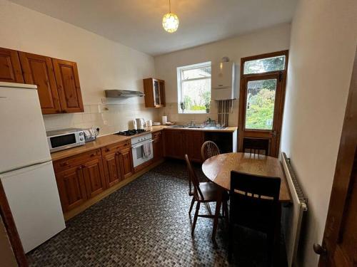 a kitchen with wooden cabinets and a table with chairs at 3 Bed Ground Floor Flat in London