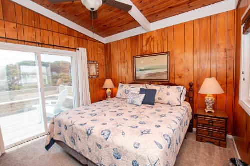 a bedroom with a bed with wooden walls and a window at Oceanside, Sun Deck, Close to beach! KH106, Annie Oakley in Kitty Hawk