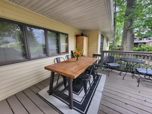 een houten tafel op een veranda met stoelen en tafels bij Hidden Oasis Close to Beach and Town in South Haven