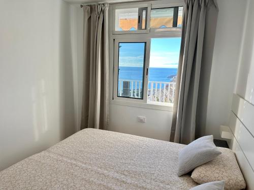 a bedroom with a bed and a large window at AMADORES BEACH VIEW APARTMENT in Amadores