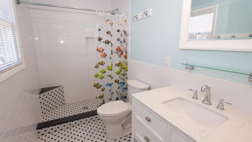 a white bathroom with a toilet and a shower at KH146, Camelot- Oceanside, Screened Porch, Close to Shopping and Restaurants! in Kitty Hawk