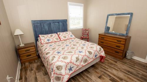 a bedroom with a bed and a dresser and a mirror at KH146, Camelot- Oceanside, Screened Porch, Close to Shopping and Restaurants! in Kitty Hawk
