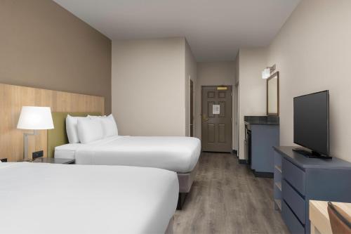 a hotel room with two beds and a flat screen tv at Country Inn & Suites by Radisson, Gainesville, FL in Gainesville