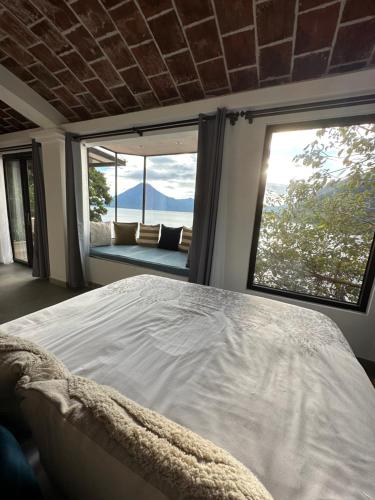 a bedroom with a large bed and large windows at Atitlan Sunset Lodge in Santa Cruz La Laguna