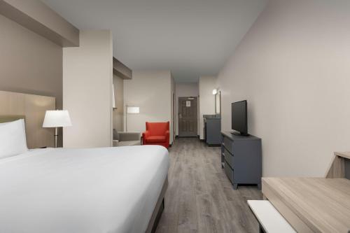 a hotel room with a bed and a red chair at Country Inn & Suites by Radisson, Gainesville, FL in Gainesville
