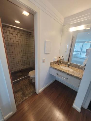 a bathroom with a sink and a toilet and a mirror at Flat Brasília Lider By Rei dos Flats in Brasília