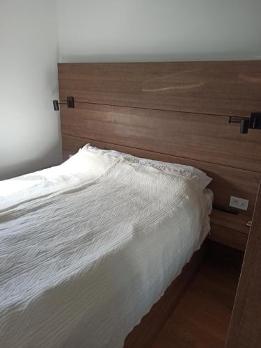 Un dormitorio con una cama blanca con cabecero de madera. en Centar Sveta, en Zlatibor