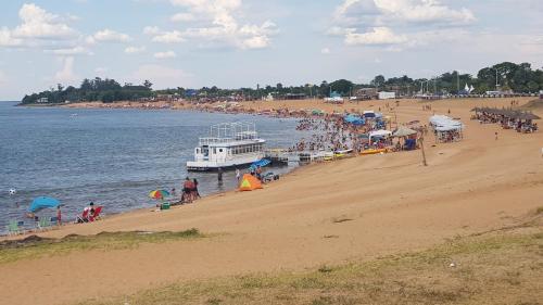 a group of people on a beach with a ferry at Cabaña Don Suso in Paso de la Patria
