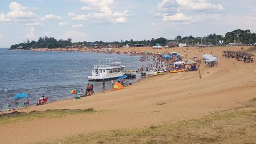 un grupo de personas en una playa con un ferry en Cabaña Don Suso en Paso de la Patria