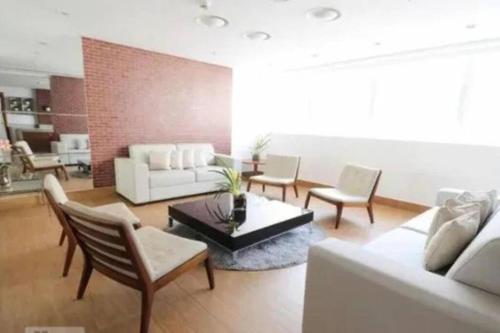 a living room with a white couch and chairs at Flat Luxo Jardim Goiás in Goiânia