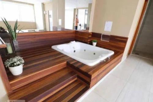 a bath tub in a bathroom with wooden floors at Flat Luxo Jardim Goiás in Goiânia