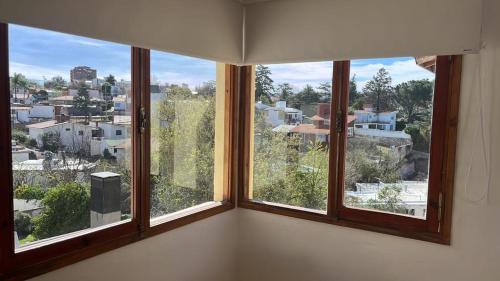 a room with three windows with a view of a city at Departamento cerca del centro - Carhue in Villa Carlos Paz