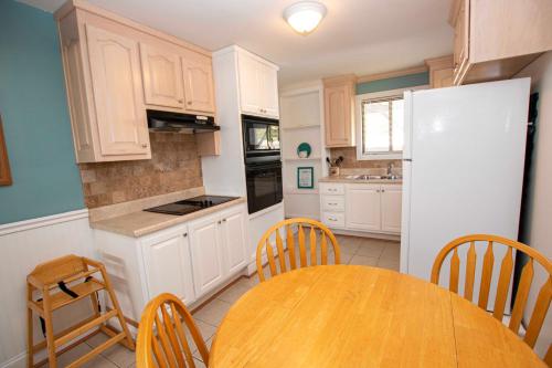 a kitchen with a table and a white refrigerator at Oceanside, Private Pool, Hot Tub, MIL Suite, KH529, Sea Turtle Sunrise in Kitty Hawk