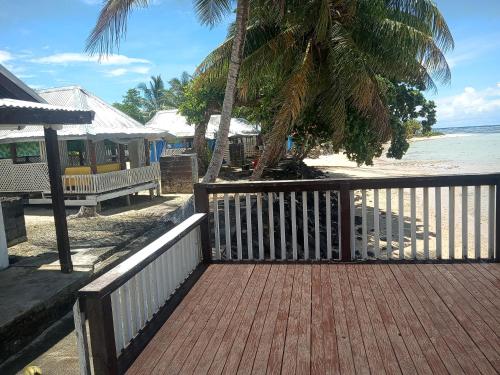 Vacation beach fale في Manase: ممشى خشبي يؤدي إلى شاطئ به سياج