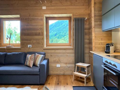 a living room with a couch and two windows at Chalet La mia Baita in Pezzo