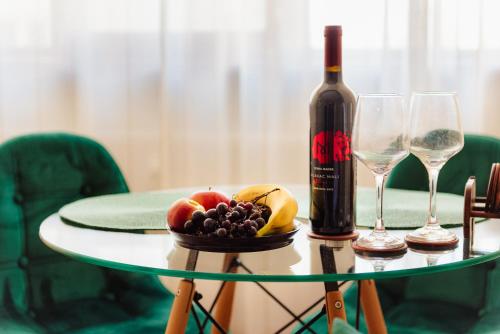 una mesa de cristal con una botella de vino y fruta en Studio @ Arena Națională Stadium, en Bucarest
