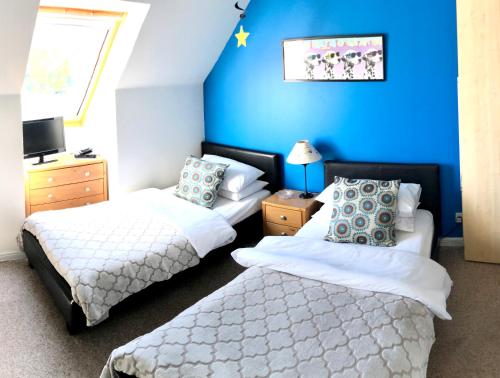 a bedroom with two beds and a blue wall at Hector's House in Aviemore