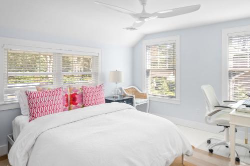 een witte slaapkamer met een bed, een bureau en ramen bij Blue Door Cottage in Cutchogue