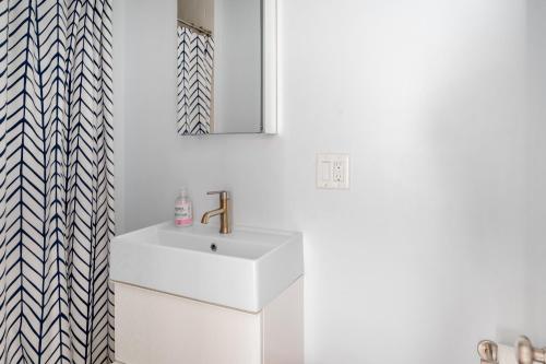 een witte badkamer met een wastafel en een spiegel bij Blue Door Cottage in Cutchogue