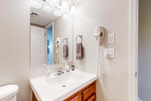 ein weißes Badezimmer mit einem Waschbecken und einem Spiegel in der Unterkunft Alpine Abode in Pigeon Forge