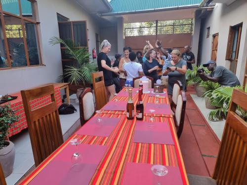 a group of people standing around a restaurant with red and purple tables at Kisanga Homestay in Moshi