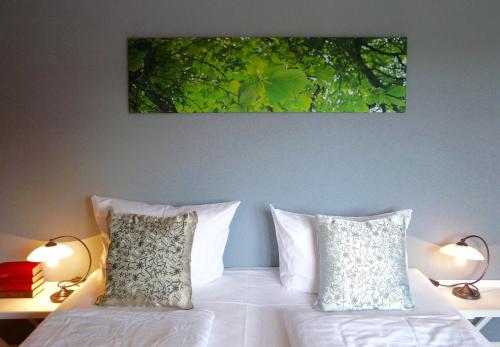 a bed with two pillows and a painting on the wall at Landfein Big Country House in Winterberg