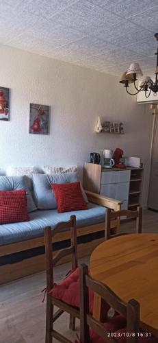 a living room with a blue couch and a table at Ustou Guzet neige, appartement de 32 M2 avec balcon dans les Pyrénées aux pieds des pistes in Ustou
