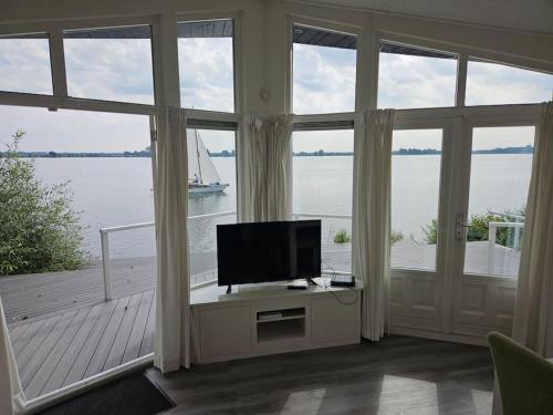 a living room with a tv and a large window at Chalet "Aan ut water" Elburg in Biddinghuizen
