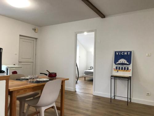 un salon avec une table et des chaises en bois dans l'établissement LE PETIT FAURE - Face aux Thermes - Calme - Parking gratuit, à Vichy