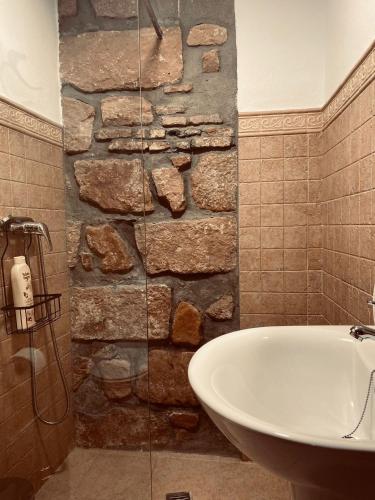 baño con lavabo y pared de piedra en Alojamientos Mestanza, en Baños de la Encina