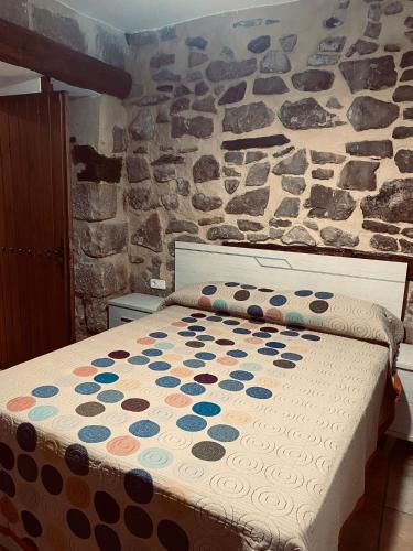 Cama en habitación con pared de piedra en Alojamientos Mestanza, en Baños de la Encina