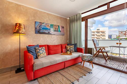 a red couch in a living room with a window at Modern Apt with Pool - Yumbo & Beach in Maspalomas