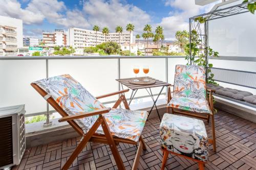 a balcony with two chairs and a table with glasses of wine at Modern Apt with Pool - Yumbo & Beach in Maspalomas