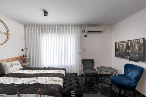 a bedroom with a bed and two chairs and a window at Motzkin sweet in Qiryat Motzkin