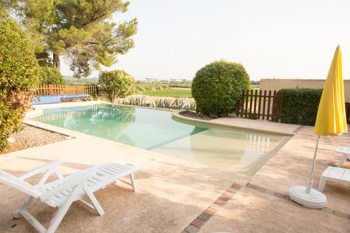 a swimming pool with two chairs and an umbrella at Domaine Sant Apolis - Cazouls les Béziers in Puisserguier
