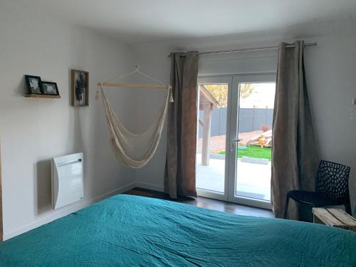 a bedroom with a blue bed and a sliding glass door at L'étape de Marcel - Aymé in Avoine