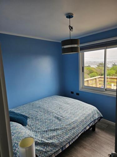- une chambre bleue avec un lit et une fenêtre dans l'établissement Vista al mar, à Concón